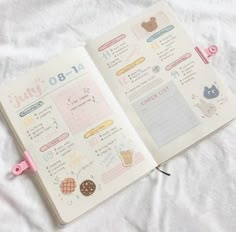 an open planner book with stickers and writing on the pages is laying on a bed