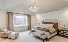 a bedroom with a bed, chair and chandelier