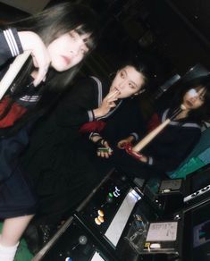 two girls are playing with an electronic device in a room full of other electronics and equipment