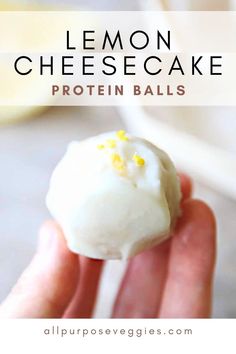 a hand holding a lemon cheesecake protein ball in it's palm with the text overlay