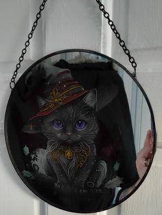 a mirror with a black cat wearing a witches hat hanging from it's side