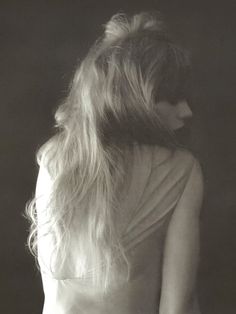 a black and white photo of a woman with her back to the camera, looking down