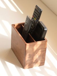 three remote controls in a wooden box on a table