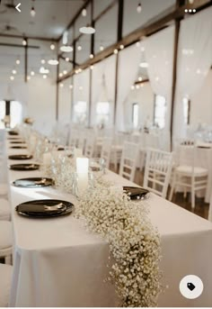 the tables are set with black plates and white linens, baby's breath