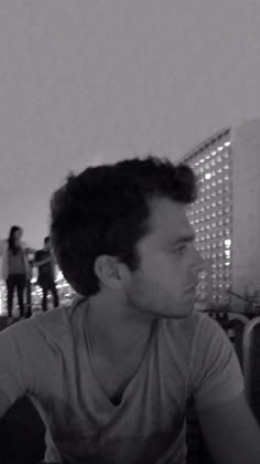 a black and white photo of a man sitting at a table in front of people