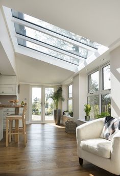 a living room filled with white furniture and lots of windows on top of it's roof