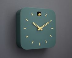 a green clock with yellow hands on a gray wall