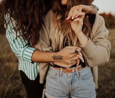 two women standing next to each other in a field with one holding the other's hand