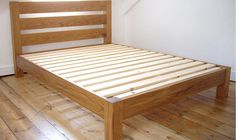 a bed with wooden slats on top of it in a room that has hard wood floors and white walls