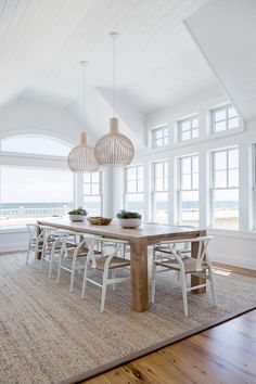 the dining room table is surrounded by white chairs and an area rug that matches the hardwood flooring