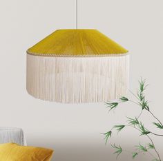 a yellow lamp hanging from a ceiling next to a plant