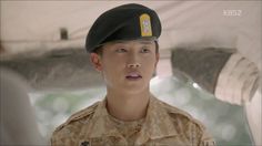 a young man in uniform is looking at the camera while wearing a hat with a yellow sticker on it