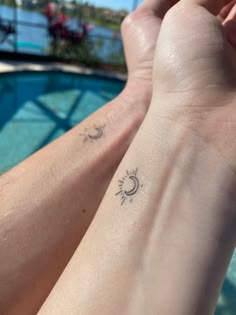 two people with tattoos on their arms next to a swimming pool