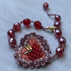 a beaded bracelet with red beads and gold clasps on a white table top