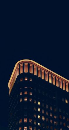 the top of a tall building lit up at night with lights shining on it's windows