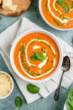 two bowls of tomato soup with basil, cheese and parmesan on the side