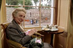 an older woman sitting in a chair next to a window