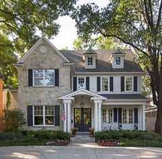 a large brick house with black shutters and white trim on the front door is shown