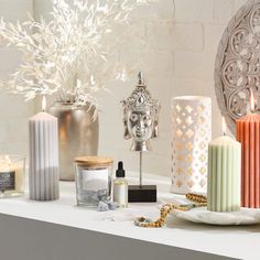 candles and other decorative items sit on a white countertop next to a candle holder