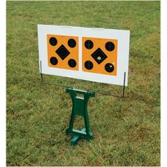 a white board with black dots on it sitting in the grass next to a green stand