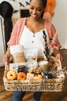 a woman holding a wicker basket full of food and snacks in her hands while smiling at the camera