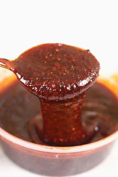 a spoon full of sauce sitting in a bowl