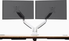 two computer monitors sitting on top of a desk with one monitor facing the other way