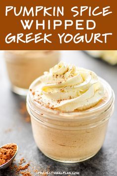 two small jars filled with whipped cream on top of a gray table next to spoons