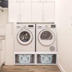 a washer and dryer in a white laundry room with wooden flooring on the side