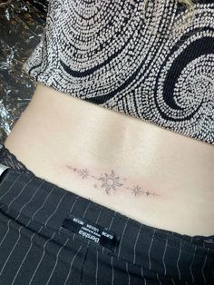 a woman's lower back tattoo with stars on her left side ribcage