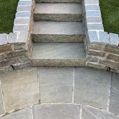 an outdoor stone walkway with steps leading up to the top and bottom, surrounded by grass