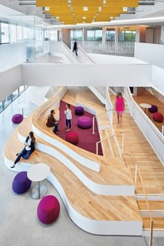 two people sitting on benches in the middle of a large room with stairs and circular seating