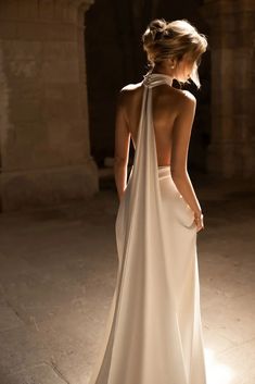 a woman in a white dress is looking down at her back with the light shining on her