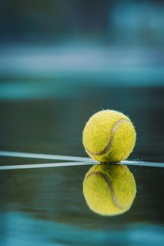 a tennis ball sitting on top of a table next to a racquet in the water