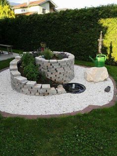 an outdoor garden with rocks and plants in the center, surrounded by green grass on either side