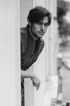 a man leaning against a wall with his hand on the door handle