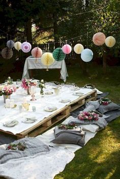 an outdoor table set up with paper lanterns