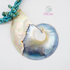 a necklace with a shell and turquoise beads on the end is shown in front of a white background