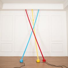 two plastic poles connected to each other in a room with white walls and wood floors