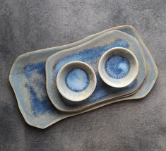 two blue and white dishes sitting on top of a gray tablecloth covered floor next to each other