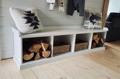 a white bench with baskets and blankets on it in front of a wall mounted coat rack