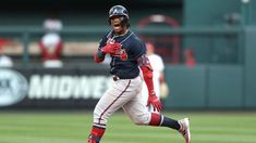 a baseball player running on the field with his glove in one hand and mouth open