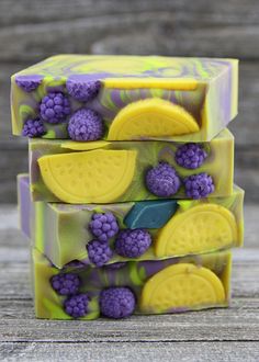 three soap bars stacked on top of each other with grapes, lemons and raspberries