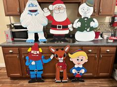 paper cutouts of santa claus, snowman, and other characters on a kitchen counter