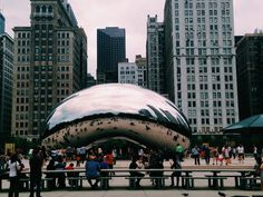 people are sitting on benches in front of a large metal object that looks like a giant banana