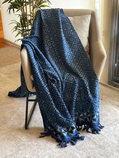 a blue blanket sitting on top of a white chair next to a potted plant