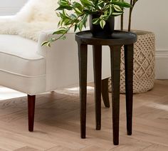 a white chair sitting next to a table with a plant on it and a vase filled with flowers