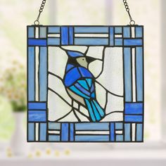 a stained glass window with a blue bird on it's side and a chain hanging from the front