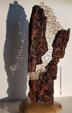 a sculpture made out of wood and wire on a table next to a white wall