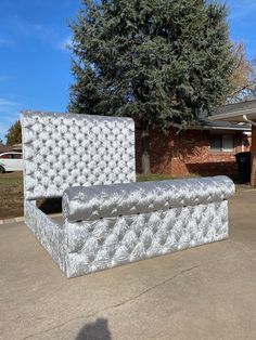 a mattress sitting in the middle of a driveway next to a tree and brick building